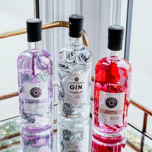 Three bottles of Collective Arts flavoured gin on a bar cart.